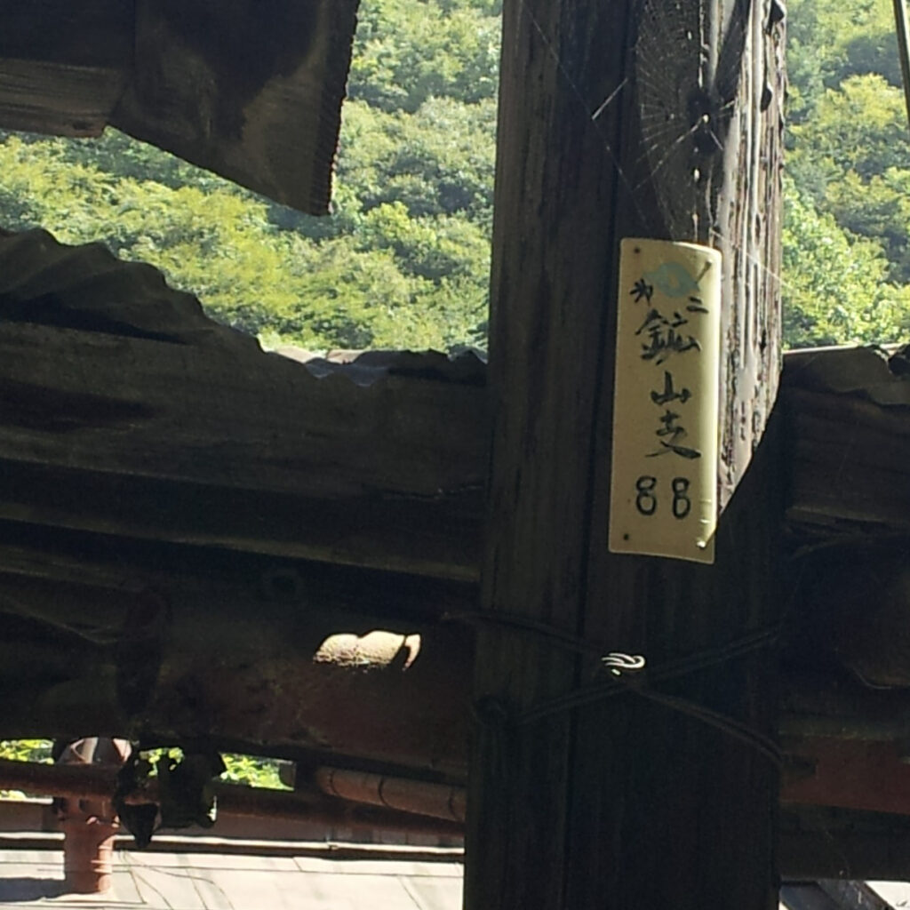 倉庫近くの電柱に残る、電電公社のマークと標識
